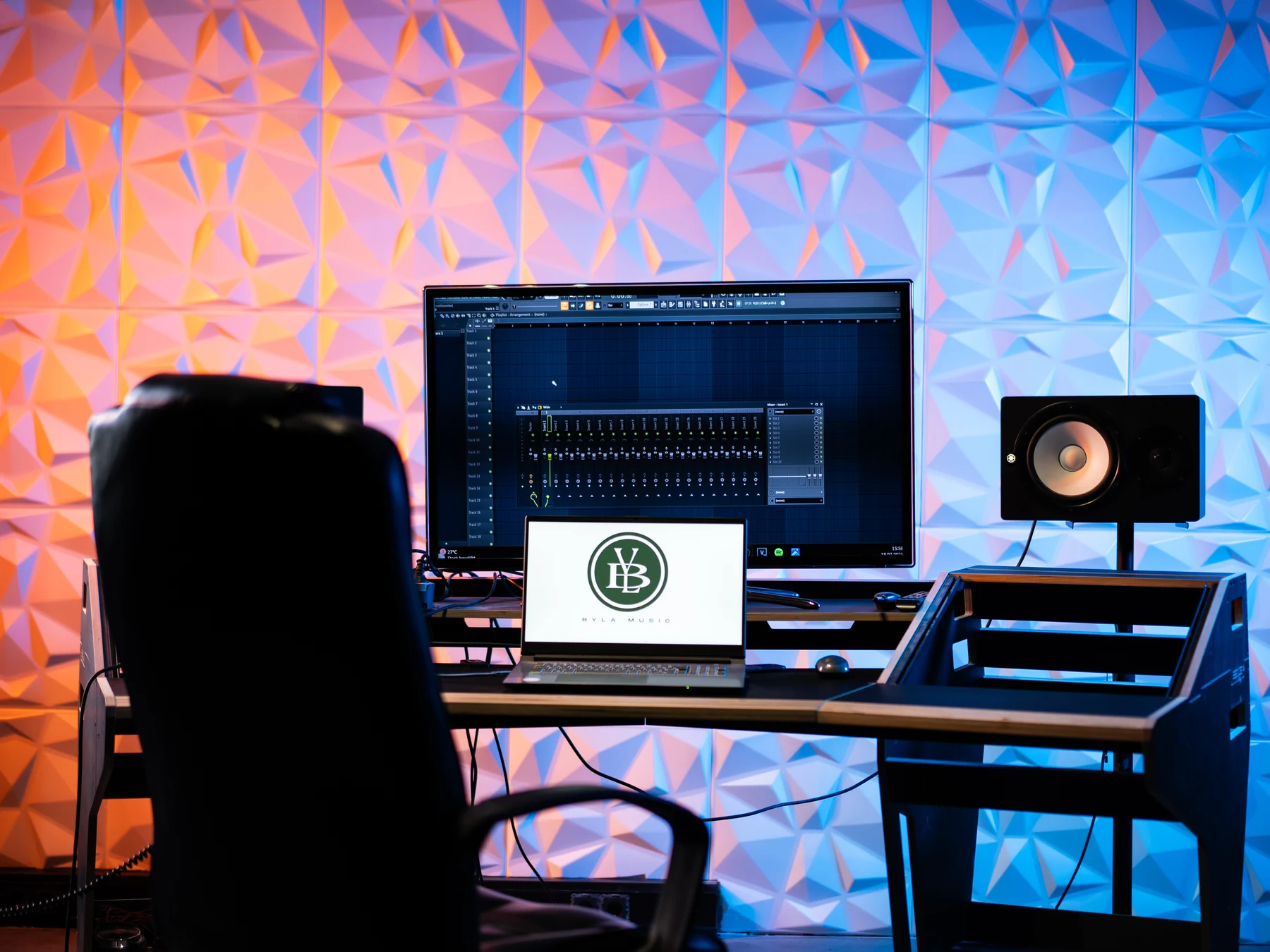 BYLA Music Regieraum mit farbig beleuchteter Akustikwand, Monitoren und Studiotisch