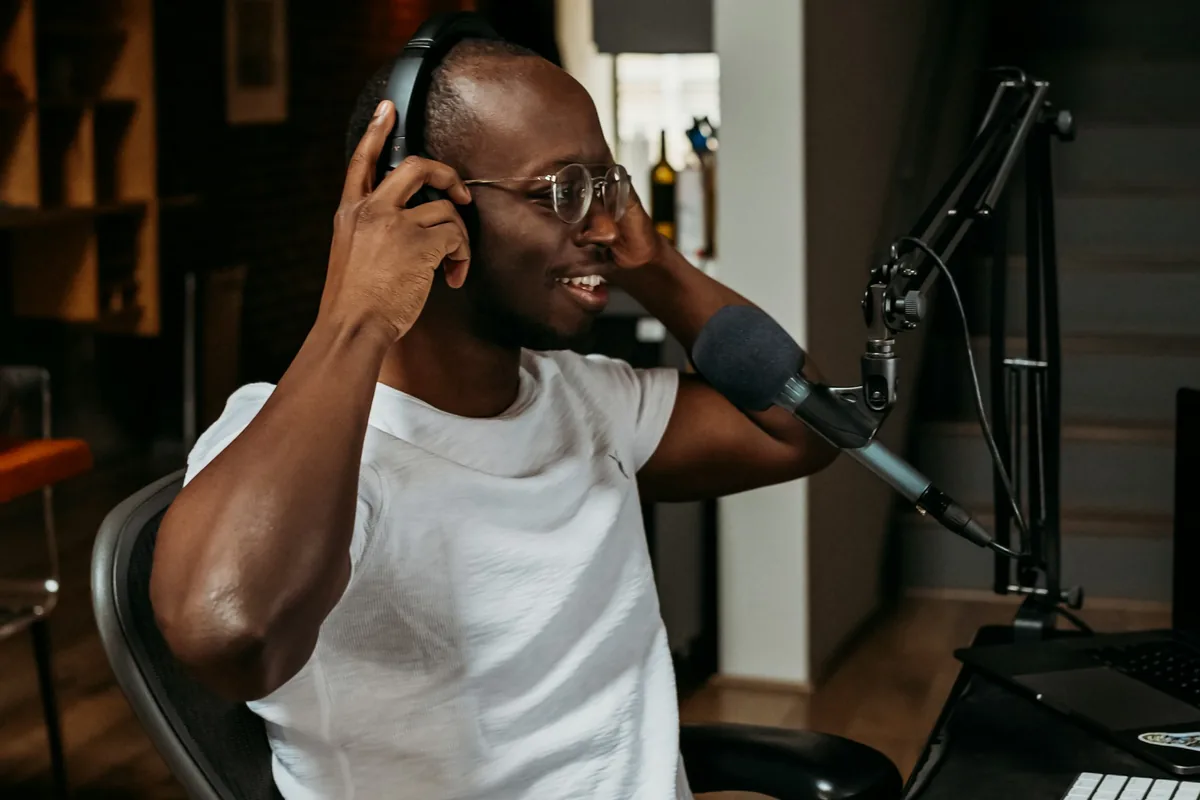 Podcaster mit Kopfhörern spricht an einem Mikrofon in einem Aufnahme-Setup