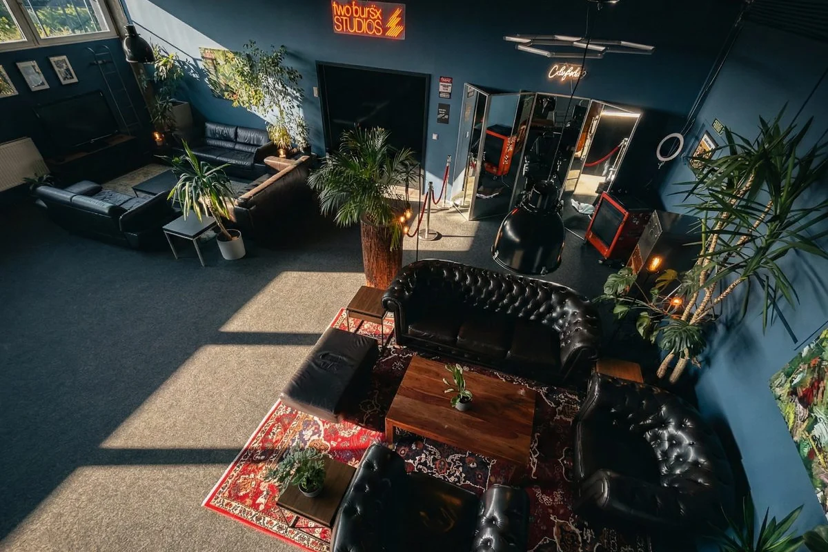 Lounge-Bereich eines Tonstudios mit Ledersofas, Pflanzen und Neon-Schriftzug